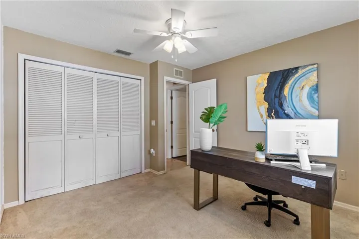 Carpeted office space with ceiling fan and a textured ceiling