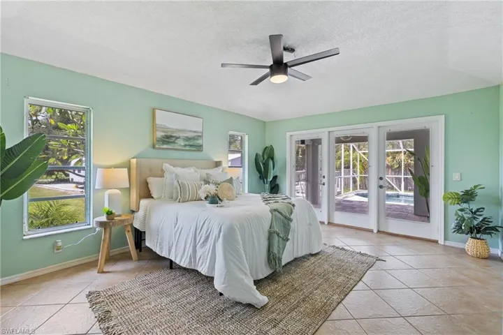 Bedroom with french doors, multiple windows, access to outside, and ceiling fan