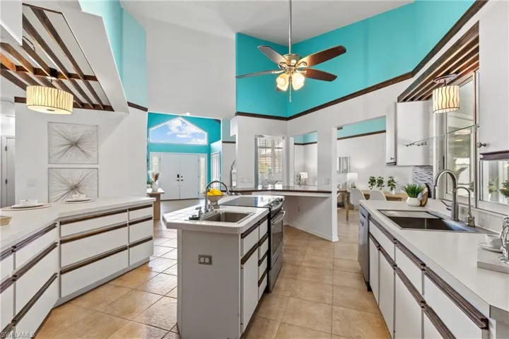 Kitchen with sink, a towering ceiling, appliances with stainless steel finishes, a center island with sink, and white cabinets