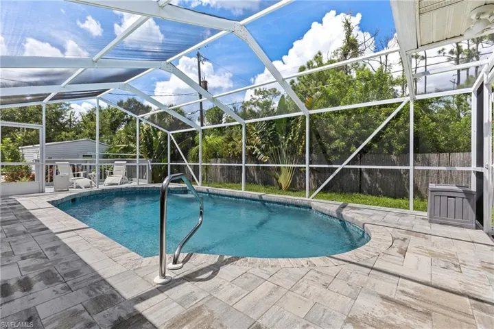 View of swimming pool with glass enclosure and a patio