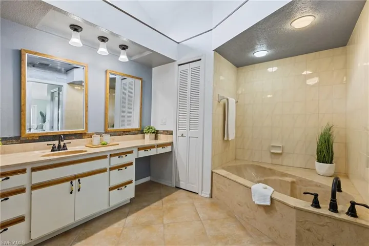 Bathroom featuring a tub, tile patterned flooring, a textured ceiling, and vanity