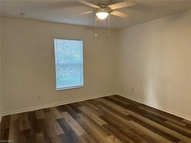 Empty room featuring dark wood-style floors and ceiling fan