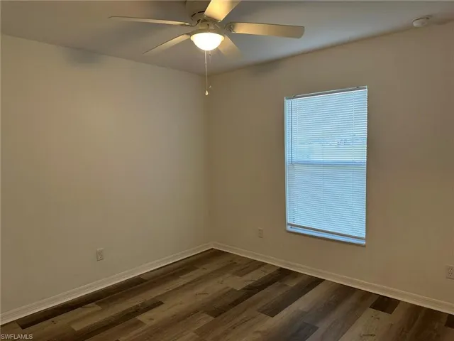 Unfurnished room with dark wood finished floors and baseboards