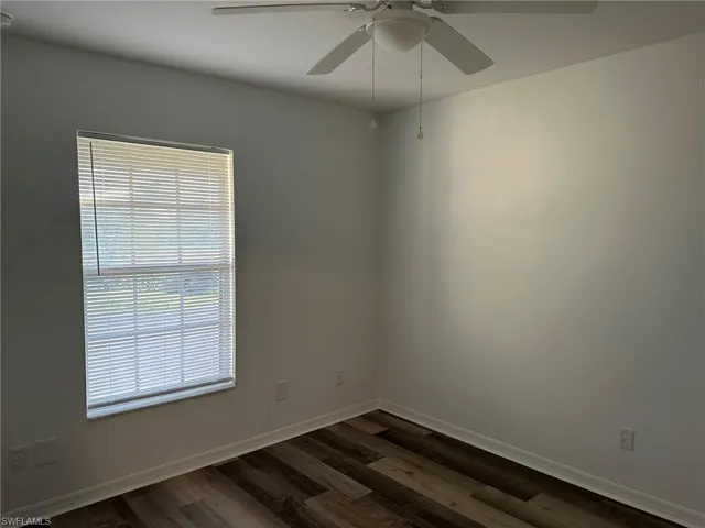 Empty room featuring dark wood-style floors and ceiling fan
