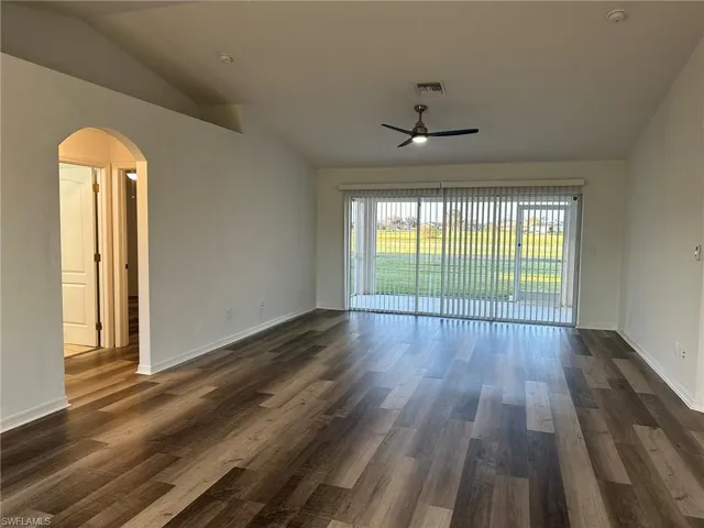Unfurnished room with lofted ceiling, dark wood finished floors, arched walkways, and a ceiling fan