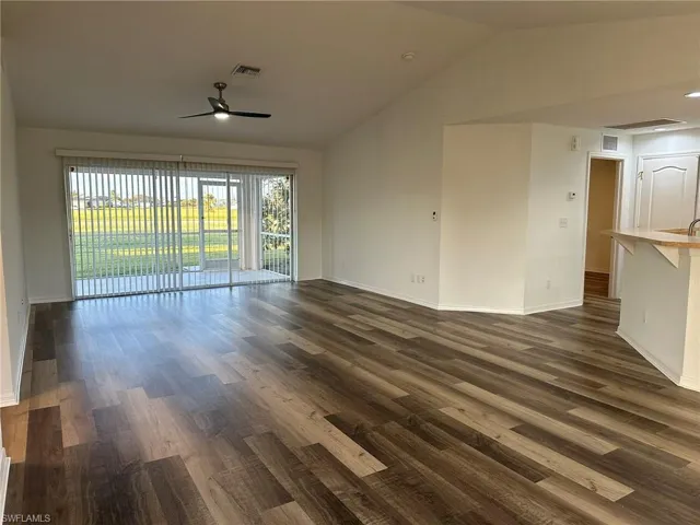 Unfurnished room with vaulted ceiling, dark wood-style floors, and ceiling fan