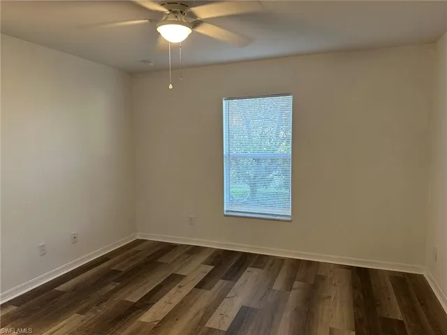 Unfurnished room featuring dark wood-type flooring and ceiling fan