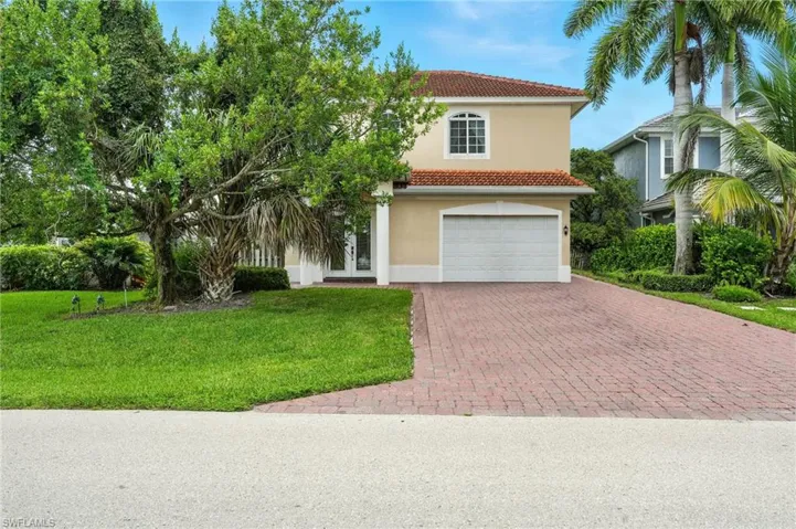 Mediterranean / spanish home with decorative driveway, a front yard, stucco siding, an attached garage, and a tiled roof