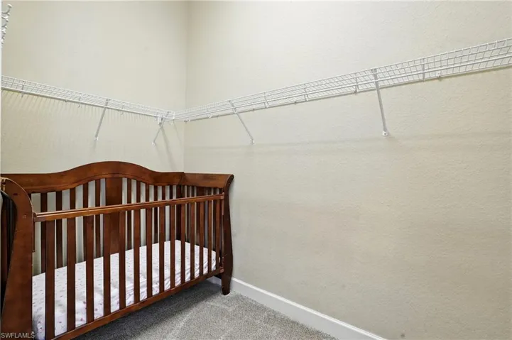 Bedroom with carpet, a crib, and a textured wall