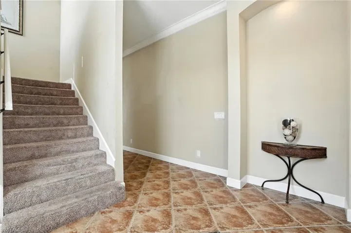 Staircase with tile patterned floors and ornamental molding