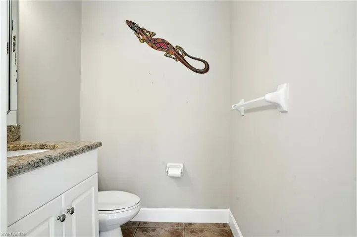 Half bath with vanity and dark tile patterned flooring