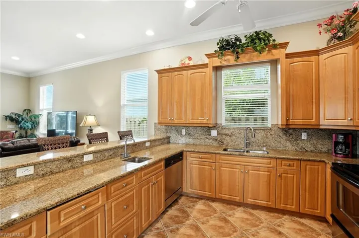 Kitchen featuring ornamental molding, light stone countertops, plenty of natural light, decorative backsplash, and recessed lighting