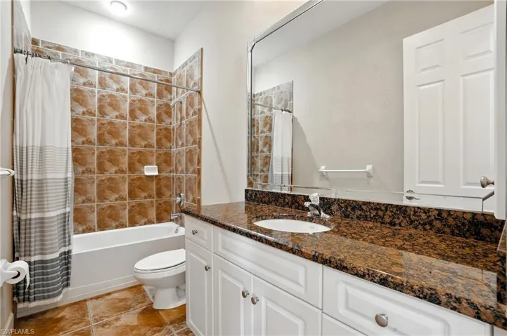 Full bathroom featuring shower / bathtub combination with curtain, vanity, and light tile patterned floors