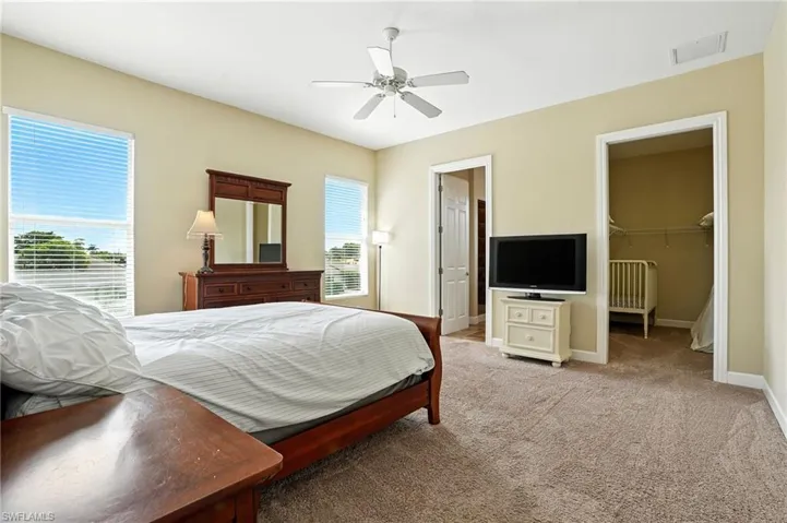 Bedroom with a walk in closet, carpet floors, and ceiling fan