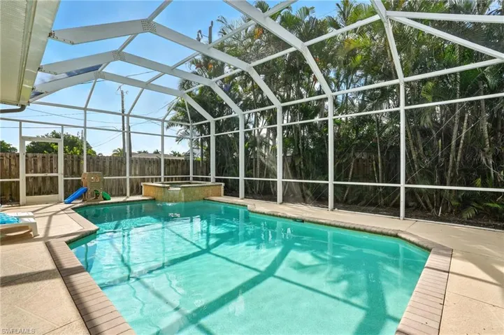 View of pool featuring a lanai, a pool with connected hot tub, and a sunroom