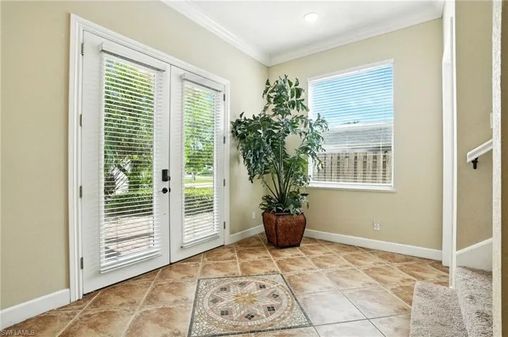 Doorway to outside featuring french doors, ornamental molding, and tile patterned floors
