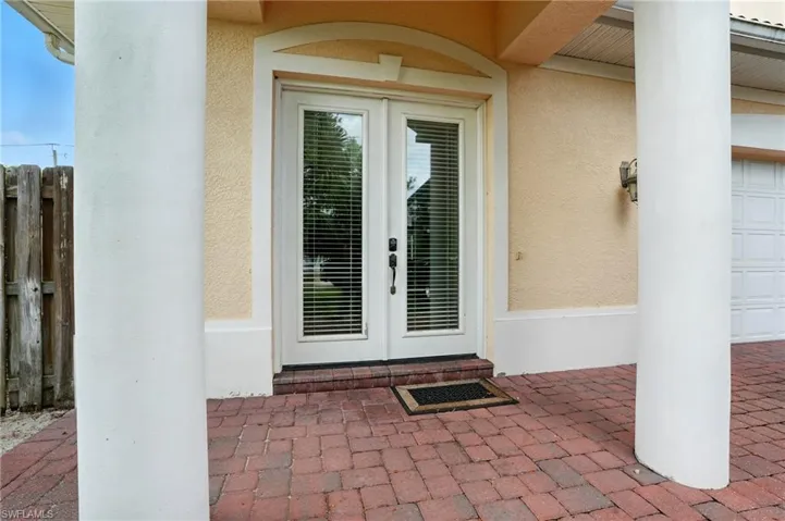 View of exterior entry with french doors, stucco siding, and a garage