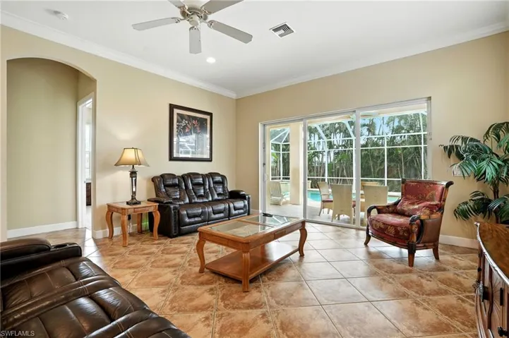 Living room featuring ornamental molding, light tile patterned flooring, recessed lighting, arched walkways, and ceiling fan