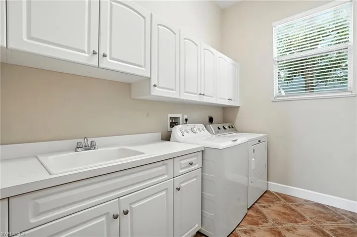 Washroom with cabinet space, independent washer and dryer, and light tile patterned flooring