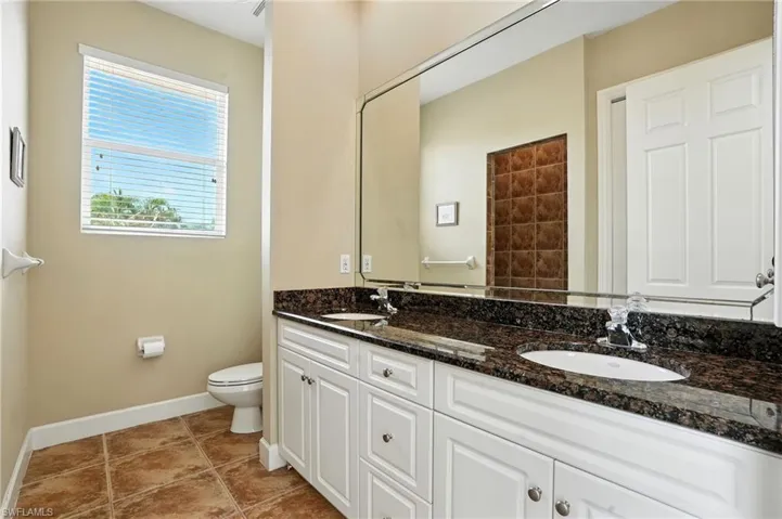 Bathroom with double vanity and light tile patterned floors