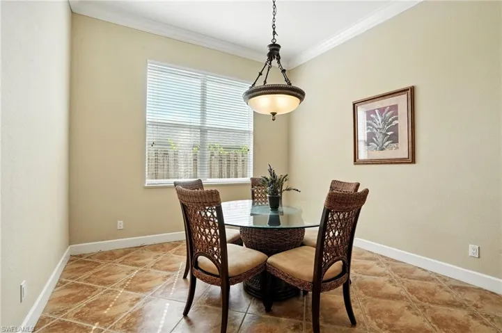 Dining area with ornamental molding and light tile patterned flooring