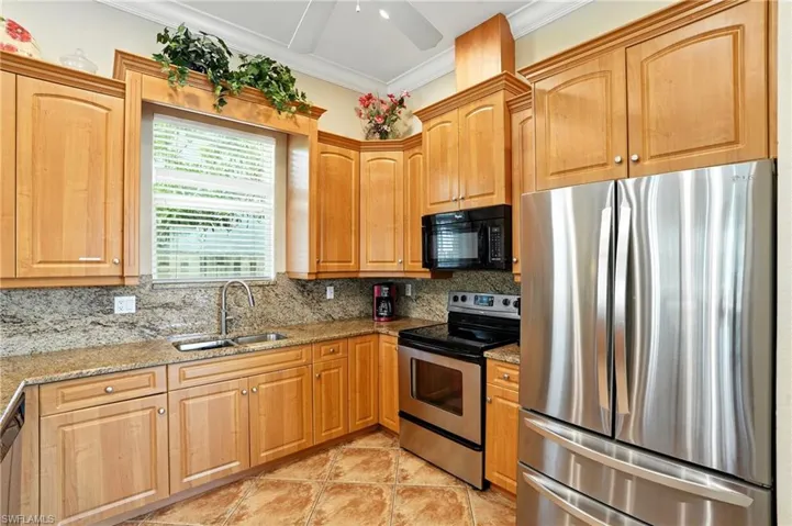 Kitchen with appliances with stainless steel finishes, ornamental molding, light stone countertops, tasteful backsplash, and a ceiling fan