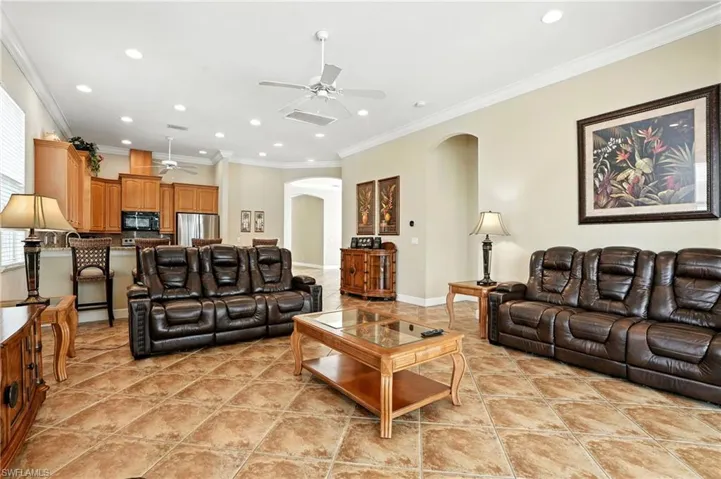 Living room featuring arched walkways, crown molding, recessed lighting, light tile patterned floors, and a ceiling fan