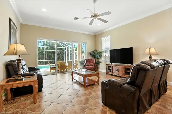 Living room featuring healthy amount of natural light, ornamental molding, a sunroom, light tile patterned floors, and a ceiling fan