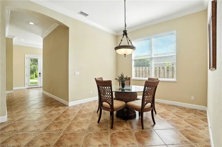 Dining space featuring arched walkways, ornamental molding, and light tile patterned flooring