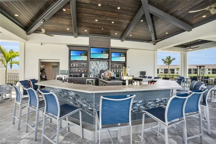 Bar with ceiling fan, beam ceiling, wood ceiling, and high vaulted ceiling