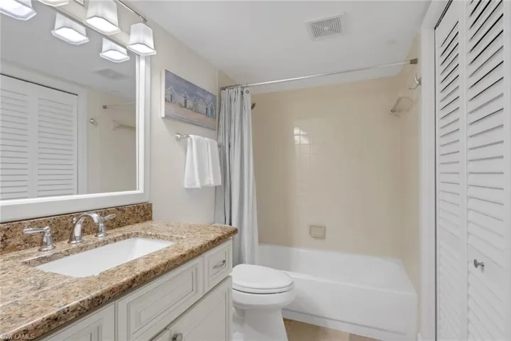 Full bath with a closet, vanity, and shower / bath combo