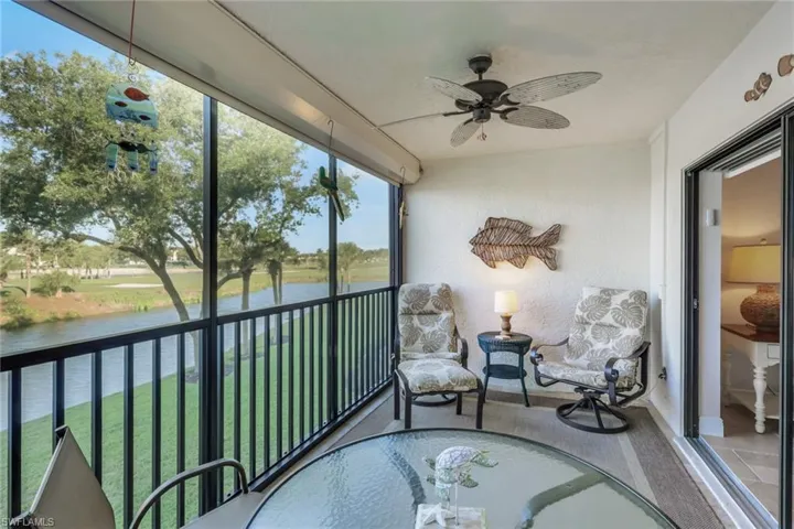 Sunroom with ceiling fan, a water view, and a balcony