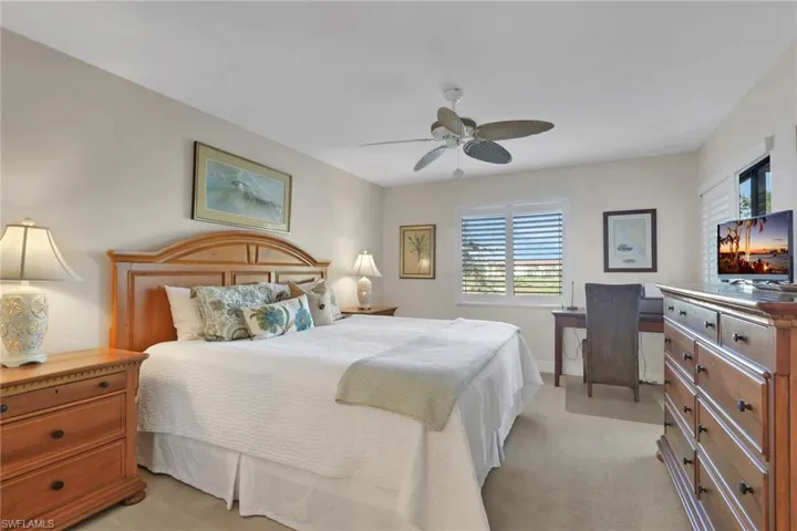 Bedroom with light colored carpet, a ceiling fan, and an office area