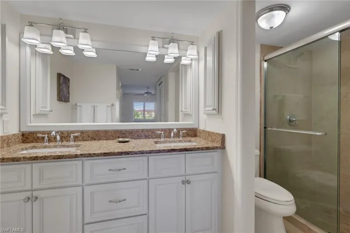 Bathroom with double vanity, a shower stall, and ceiling fan