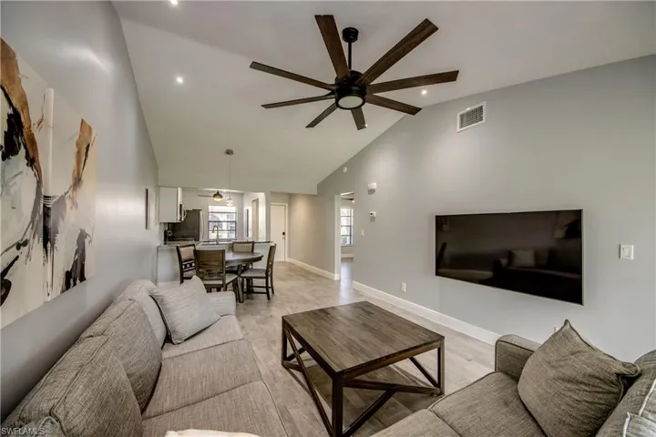 Living room with ceiling fan, vaulted ceiling, and light wood-type flooring