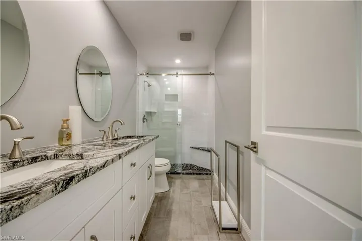 Bathroom featuring walk in shower, vanity, and toilet