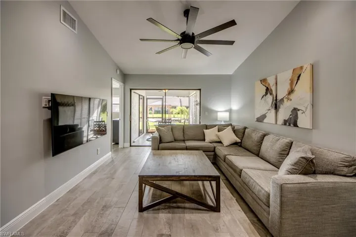 Living room featuring ceiling fan, light hardwood / wood-style flooring, and vaulted ceiling