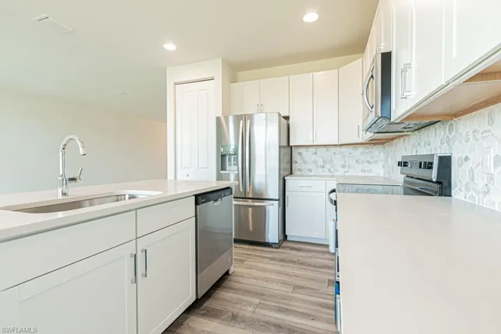 Kitchen with light wood-type flooring, white cabinetry, sink, and appliances with stainless steel finishes