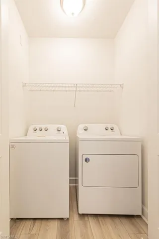 Washroom with separate washer and dryer and light wood-type flooring