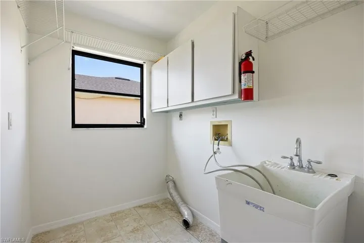 Laundry area featuring light tile floors, cabinets, hookup for a washing machine, and hookup for an electric dryer