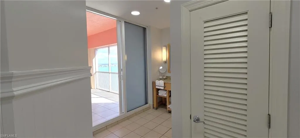 Hallway featuring light tile patterned flooring, a water view, and recessed lighting