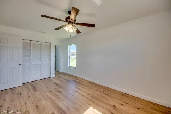 Unfurnished bedroom with light wood-type flooring, a closet, and a ceiling fan