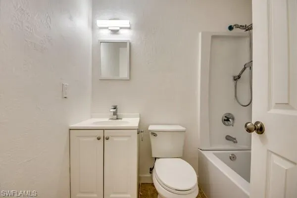 Bathroom with a textured wall, vanity, and shower / washtub combination