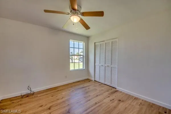 Unfurnished bedroom with light wood-type flooring, ceiling fan, and a closet