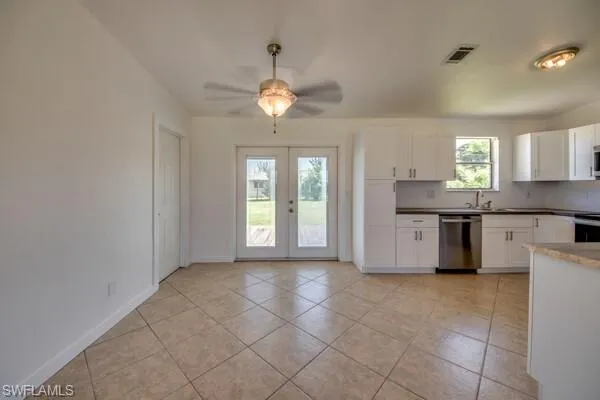Kitchen with white cabinets, a ceiling fan, stainless steel appliances, and light tile patterned floors