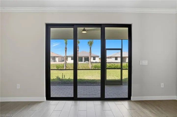 Doorway featuring crown molding, wood finish floors, and a residential view