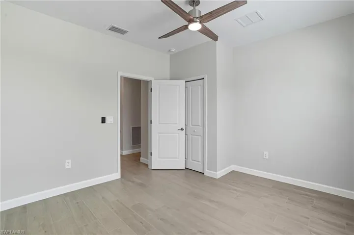 Unfurnished bedroom with light wood-style floors, ceiling fan, and a closet