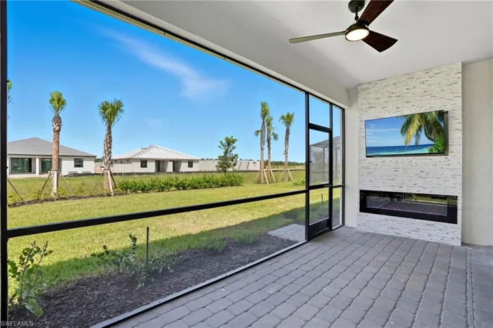 Unfurnished sunroom featuring a ceiling fan and a glass covered fireplace