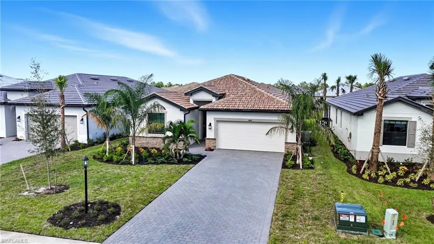View of front facade with decorative driveway, stucco siding, an attached garage, and a front lawn