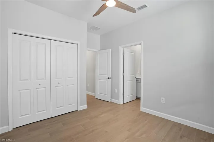 Unfurnished bedroom with light wood-style floors, a ceiling fan, a closet, and connected bathroom